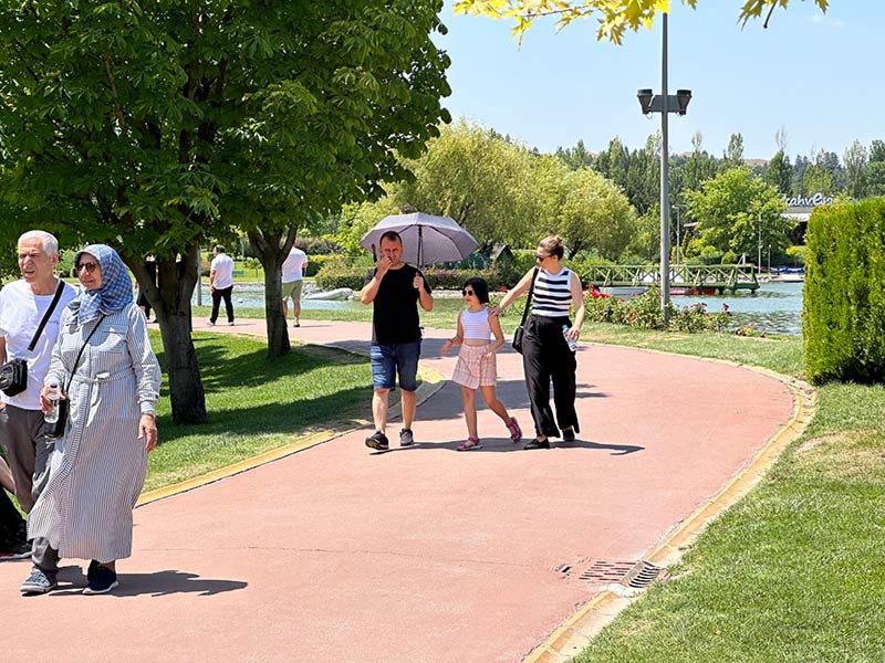 Yüksek sıcaklık sebebiyle bunalan vatandaşlar, güneşin zararlı ışınlarından korunabilmek için şemsiye kullandı.